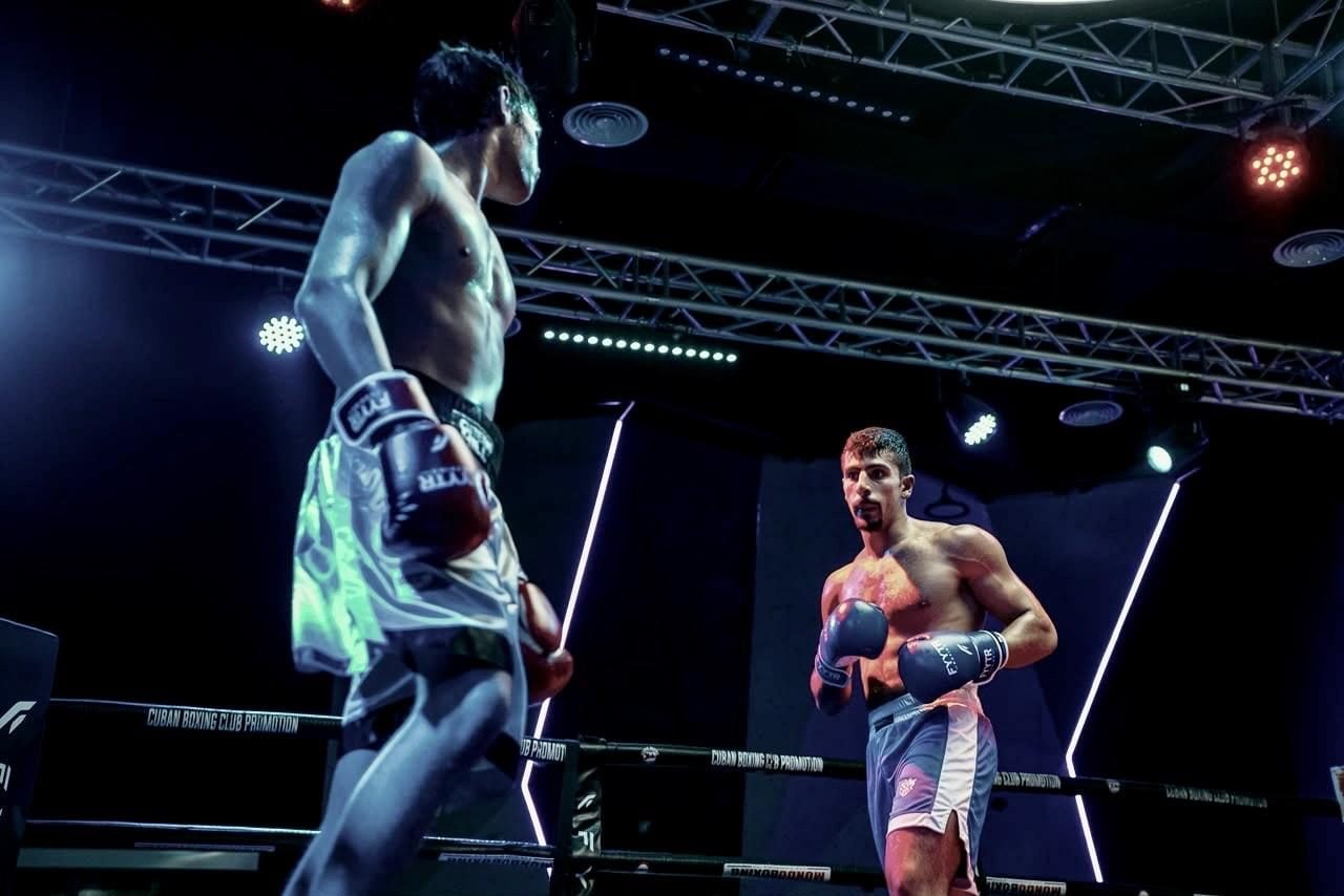 Two boxers circling under ring lights at a fight night, both in FYYTR gloves