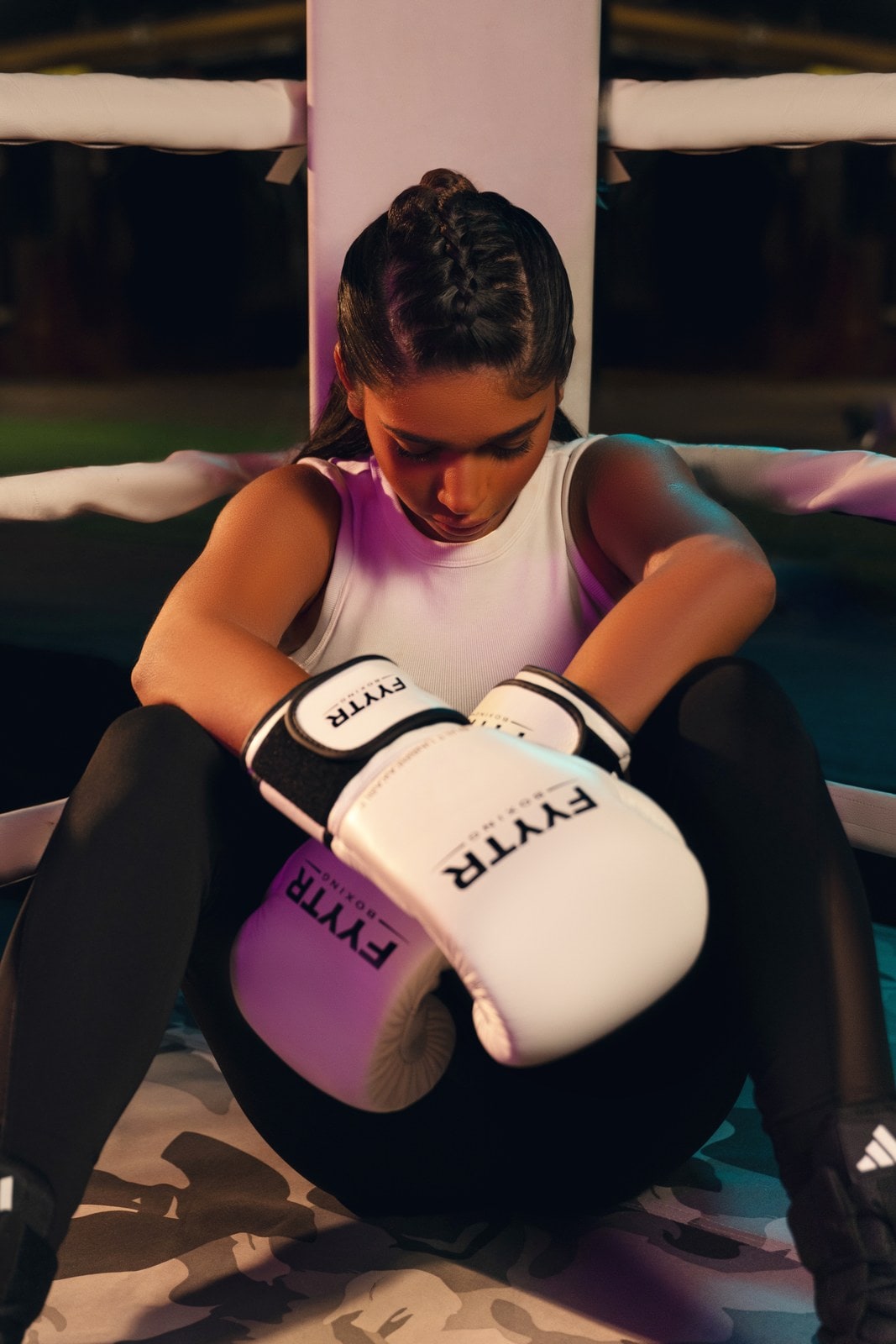 Woman resting in the ring corner wearing white FYYTR boxing gloves