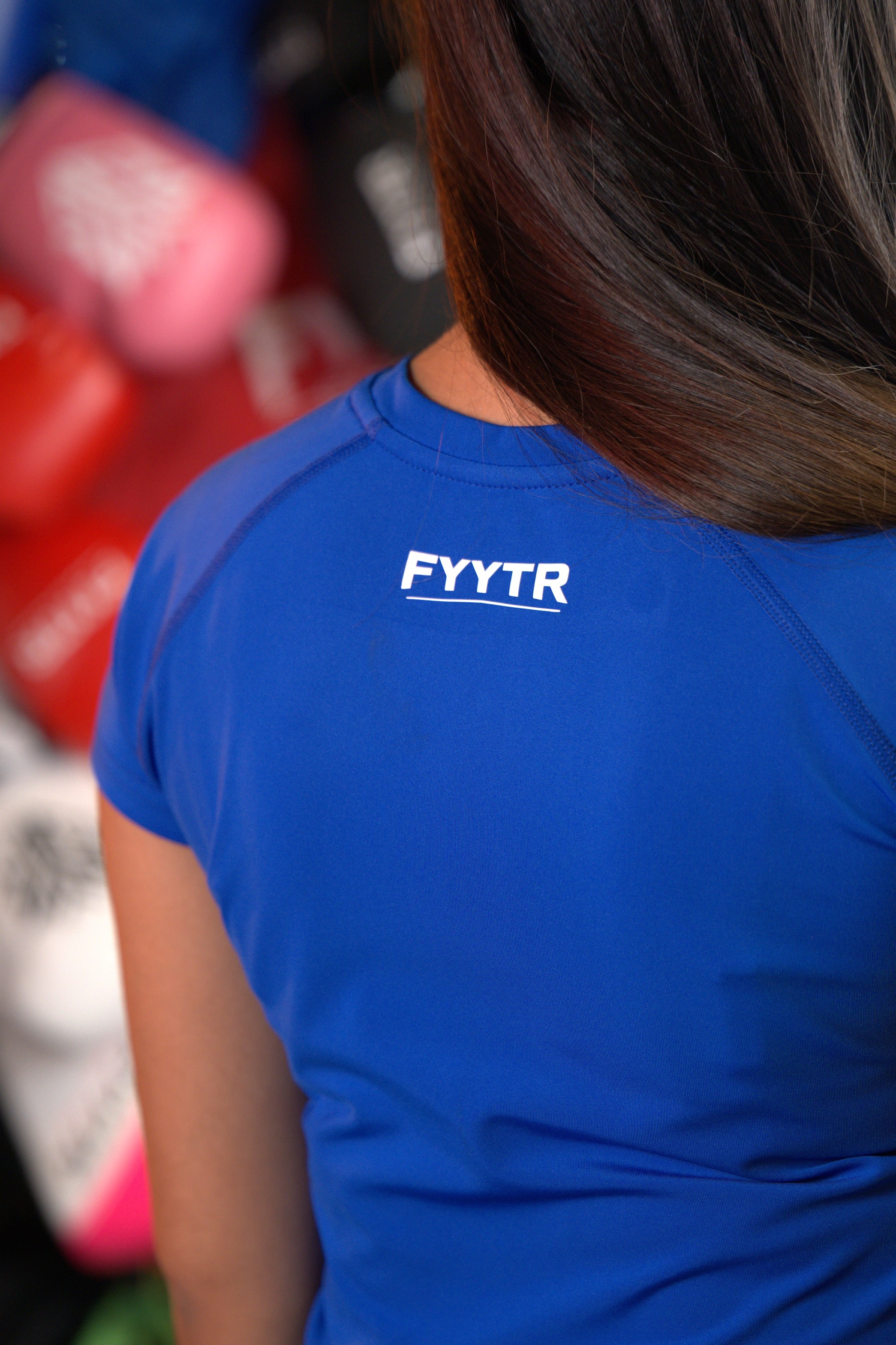 Boxer in a blue FYYTR tee in the gym, glove wall behind