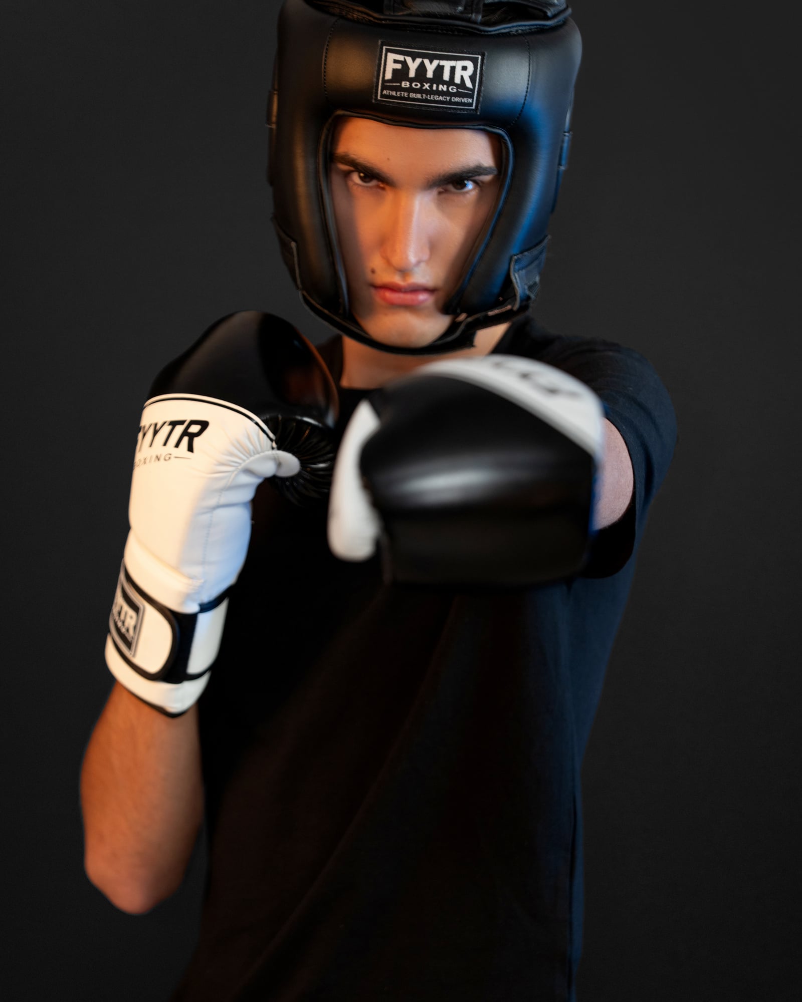 Fighter in a black headguard throwing a straight punch in white training gloves
